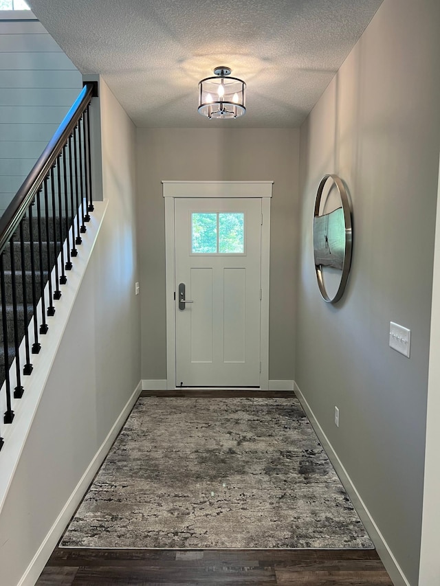 doorway to outside with a textured ceiling and dark wood-type flooring