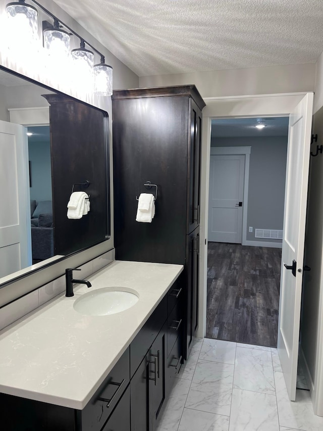 bathroom with a textured ceiling, hardwood / wood-style floors, and vanity