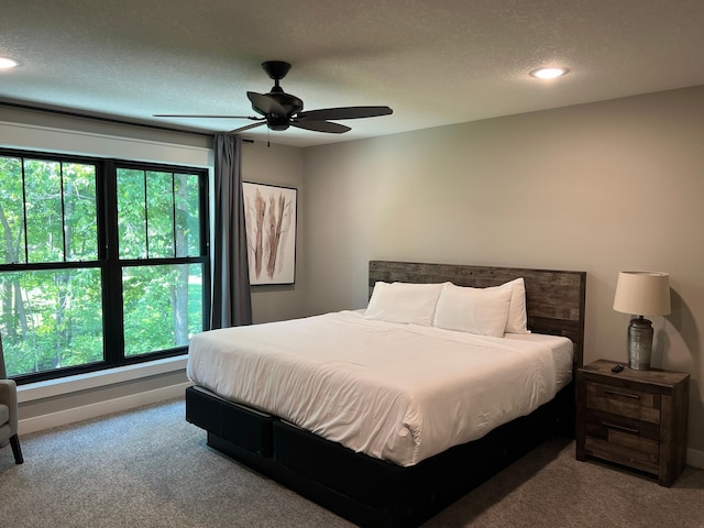 carpeted bedroom with ceiling fan, a textured ceiling, and multiple windows