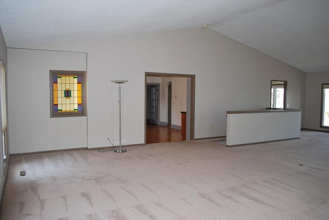 spare room with carpet floors, high vaulted ceiling, and a textured ceiling