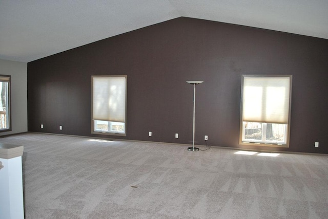 spare room featuring lofted ceiling, light carpet, and plenty of natural light