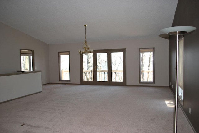 empty room featuring light colored carpet, vaulted ceiling, and an inviting chandelier