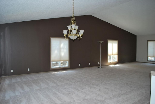 carpeted spare room featuring lofted ceiling, a notable chandelier, and a wealth of natural light