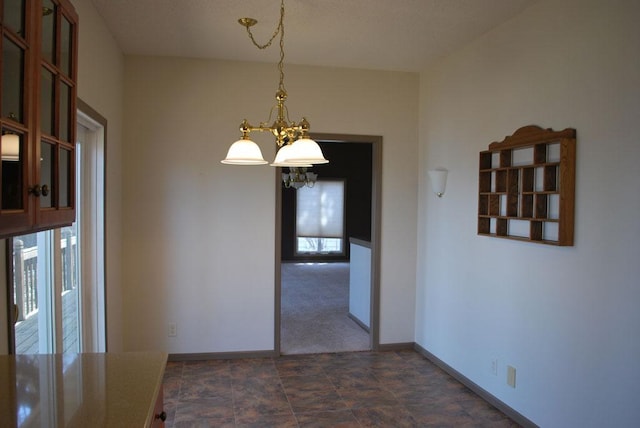 unfurnished dining area featuring dark tile flooring and a chandelier