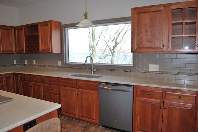 kitchen featuring dark tile flooring, backsplash, hanging light fixtures, dishwasher, and sink