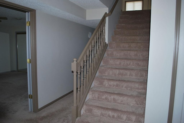 staircase with a textured ceiling and carpet