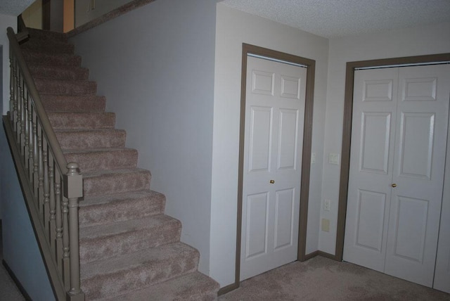 staircase featuring a textured ceiling and carpet flooring