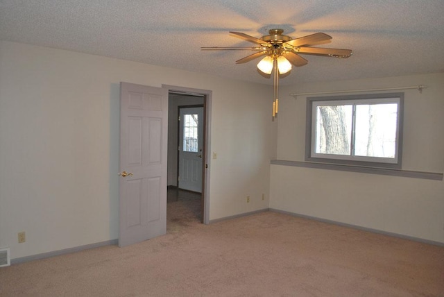 carpeted empty room featuring ceiling fan and a textured ceiling