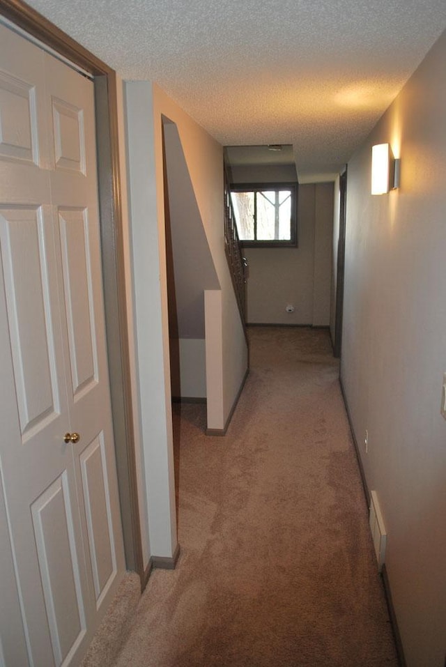 hallway with light carpet and a textured ceiling