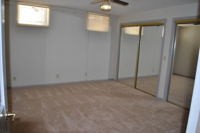 unfurnished bedroom featuring multiple closets, ceiling fan, and carpet floors