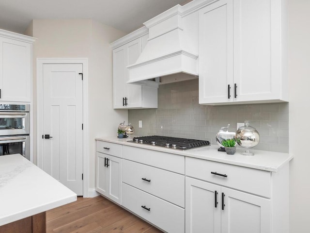 kitchen featuring tasteful backsplash, stainless steel appliances, light hardwood / wood-style flooring, and white cabinetry