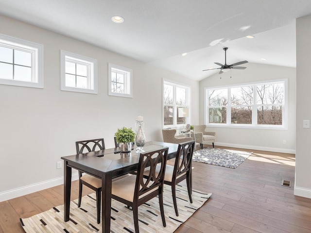 dining room with ceiling fan, vaulted ceiling, and light hardwood / wood-style flooring