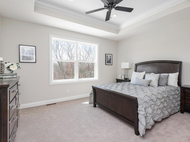 bedroom with light carpet, ornamental molding, ceiling fan, and a tray ceiling