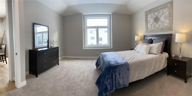 bedroom with baseboards, vaulted ceiling, and light colored carpet