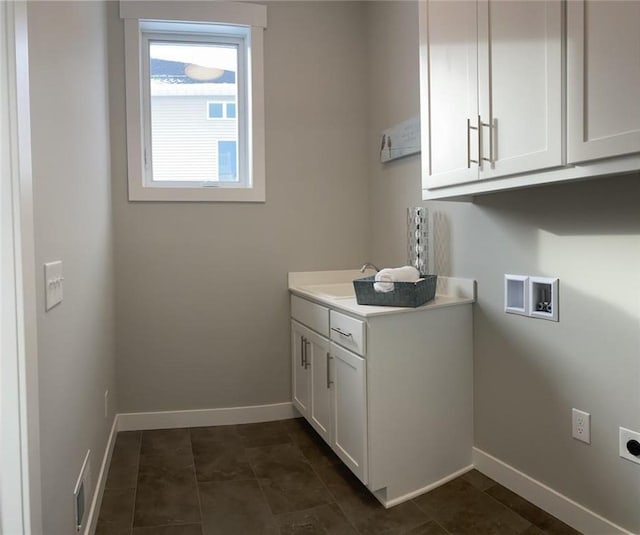 laundry room with hookup for a washing machine, hookup for an electric dryer, a sink, baseboards, and cabinet space