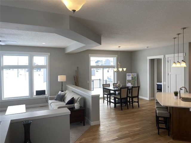 living area featuring dark wood-style floors, baseboards, a textured ceiling, and ceiling fan with notable chandelier