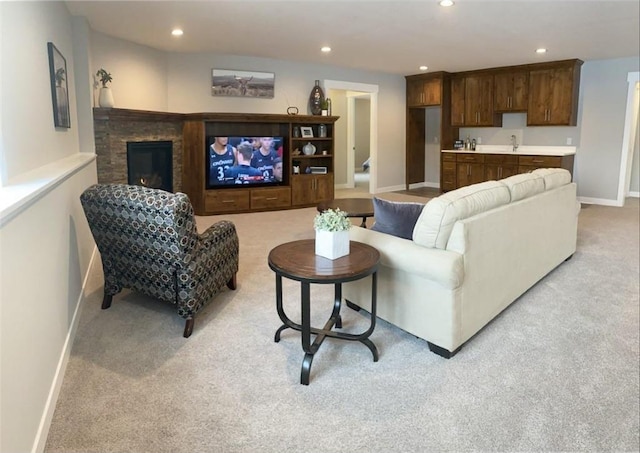 living room with recessed lighting, a glass covered fireplace, and light colored carpet