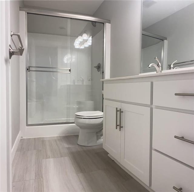 full bathroom featuring toilet, a shower stall, and vanity