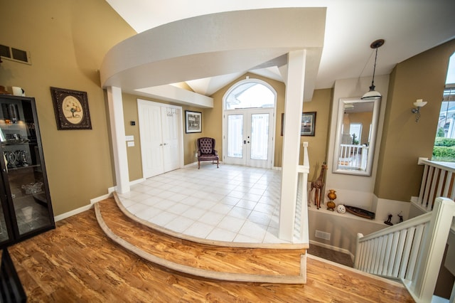 entryway with vaulted ceiling, light hardwood / wood-style floors, a wealth of natural light, and french doors