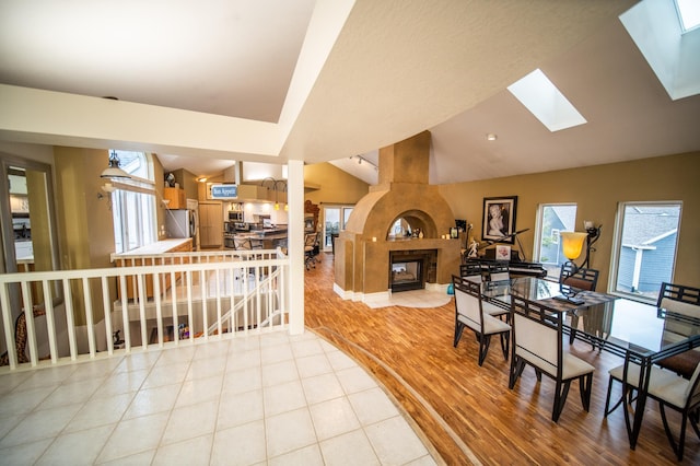 dining space with light hardwood / wood-style floors, lofted ceiling with skylight, and a premium fireplace