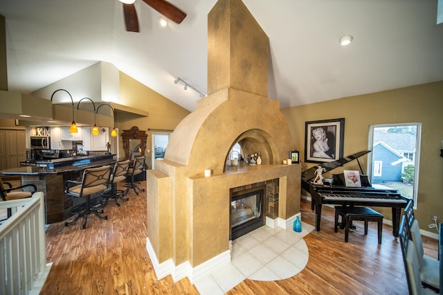 kitchen with decorative light fixtures, ceiling fan, a fireplace, and light hardwood / wood-style flooring