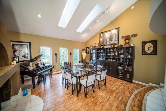 dining room featuring vaulted ceiling with skylight and light hardwood / wood-style floors