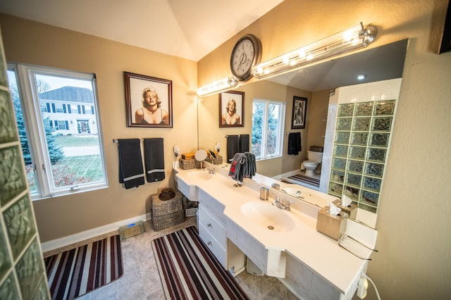 bathroom with a wealth of natural light, vanity, lofted ceiling, and toilet