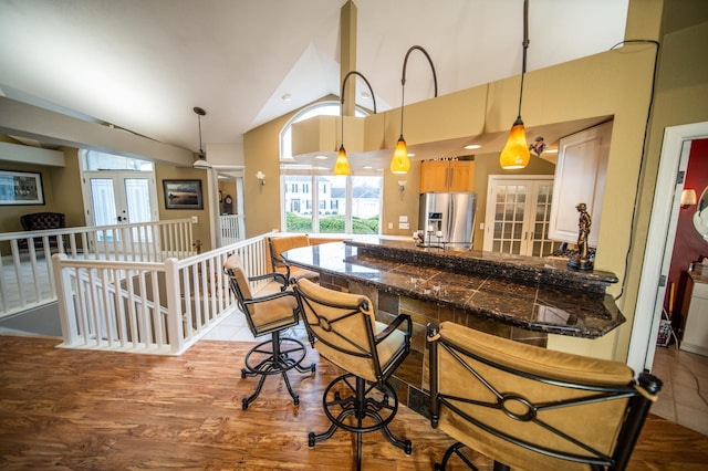 kitchen featuring stainless steel fridge, french doors, pendant lighting, and a kitchen breakfast bar