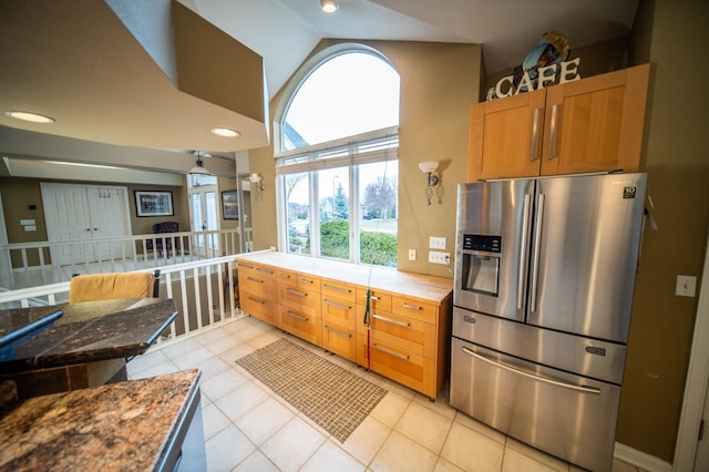 kitchen with light tile patterned floors, stainless steel refrigerator with ice dispenser, and high vaulted ceiling