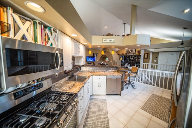 kitchen featuring white cabinets, sink, light tile patterned floors, kitchen peninsula, and stainless steel appliances