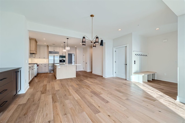 kitchen with a center island, decorative light fixtures, light wood-type flooring, a notable chandelier, and stainless steel built in refrigerator