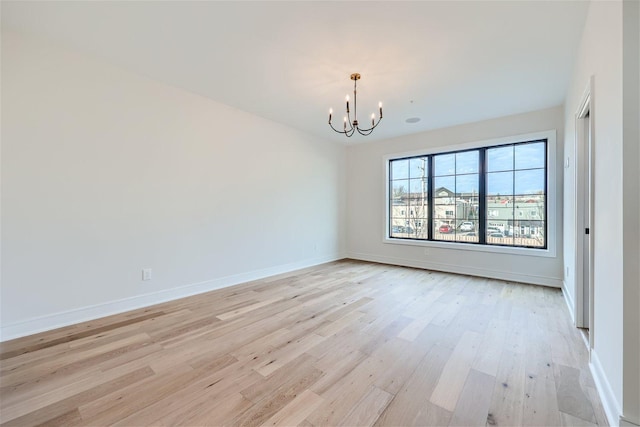 empty room featuring light wood-type flooring and a notable chandelier