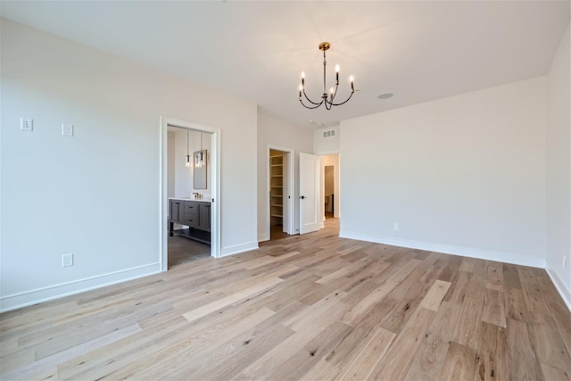 interior space with ensuite bathroom, a closet, a spacious closet, light hardwood / wood-style floors, and a chandelier