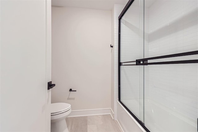 bathroom featuring shower / bath combination with glass door and toilet