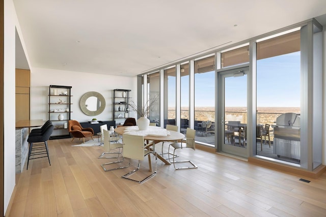 dining room featuring light wood-type flooring and floor to ceiling windows