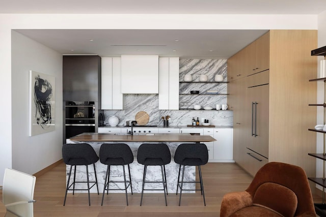 kitchen with decorative backsplash, light hardwood / wood-style flooring, and a kitchen breakfast bar