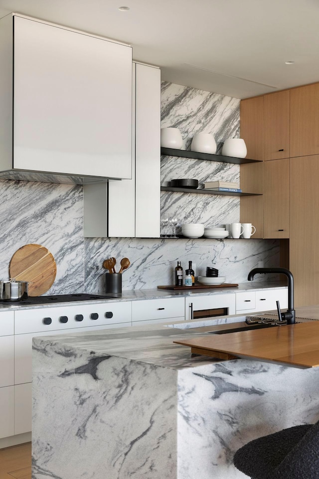 kitchen with white cabinetry, light hardwood / wood-style flooring, tasteful backsplash, and sink