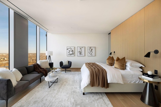 bedroom with expansive windows and light hardwood / wood-style flooring