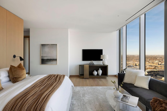 bedroom featuring a wall of windows and light hardwood / wood-style flooring