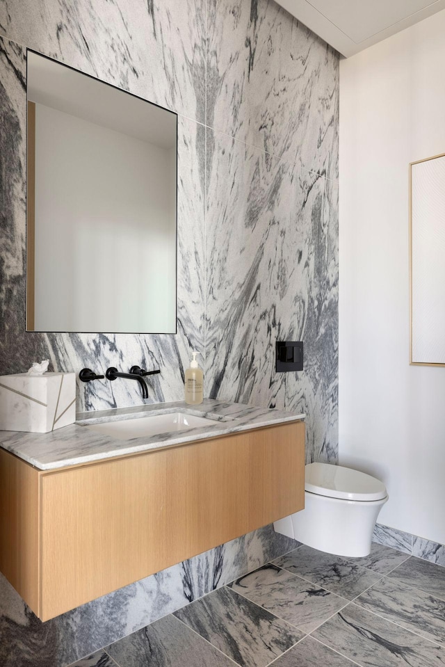 bathroom with toilet, vanity, and tile walls