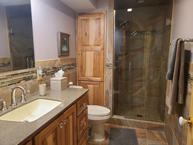 bathroom featuring vanity, tile patterned flooring, a shower with shower door, tile walls, and toilet