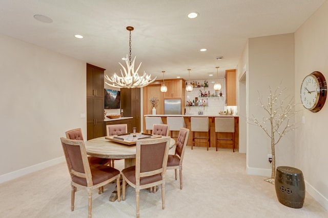 dining area featuring a chandelier, indoor bar, and light carpet