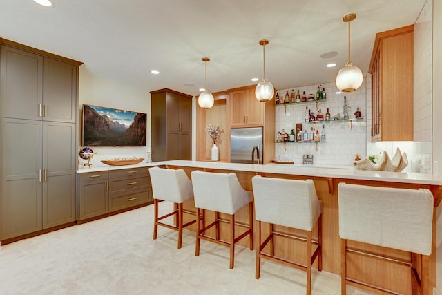 kitchen featuring tasteful backsplash, a breakfast bar, decorative light fixtures, light carpet, and high end fridge