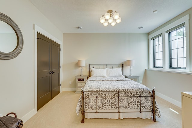 bedroom with light carpet, an inviting chandelier, and a closet