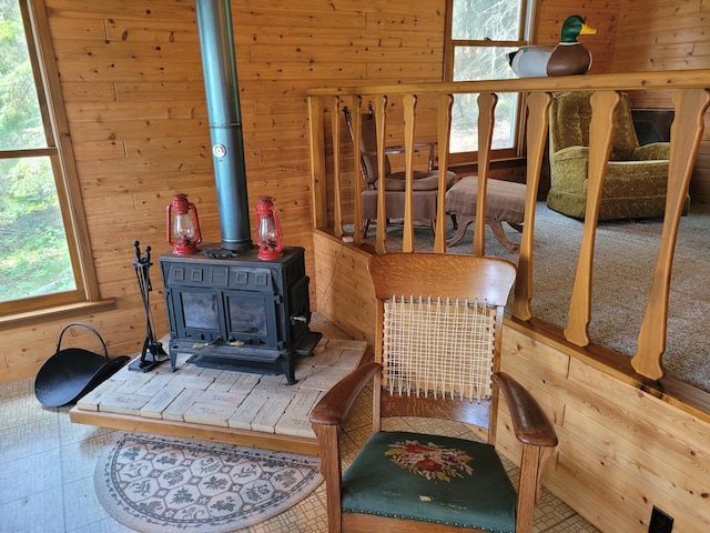 interior space with wood walls, a wood stove, and tile floors