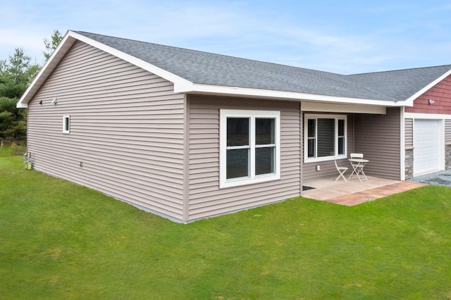 rear view of house featuring a garage, a lawn, and a patio