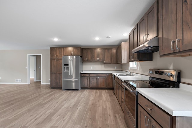 kitchen with dark brown cabinetry, light wood-type flooring, stainless steel appliances, and sink