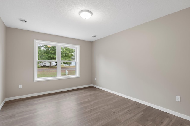 spare room with hardwood / wood-style floors and a textured ceiling