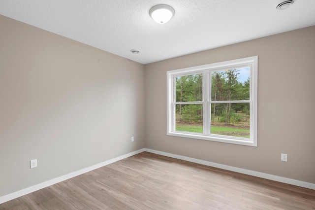 spare room featuring light hardwood / wood-style floors and a textured ceiling