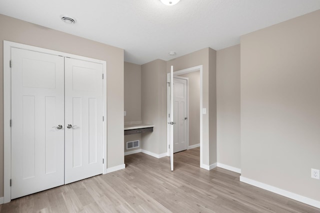 unfurnished bedroom featuring light hardwood / wood-style floors, a textured ceiling, and a closet